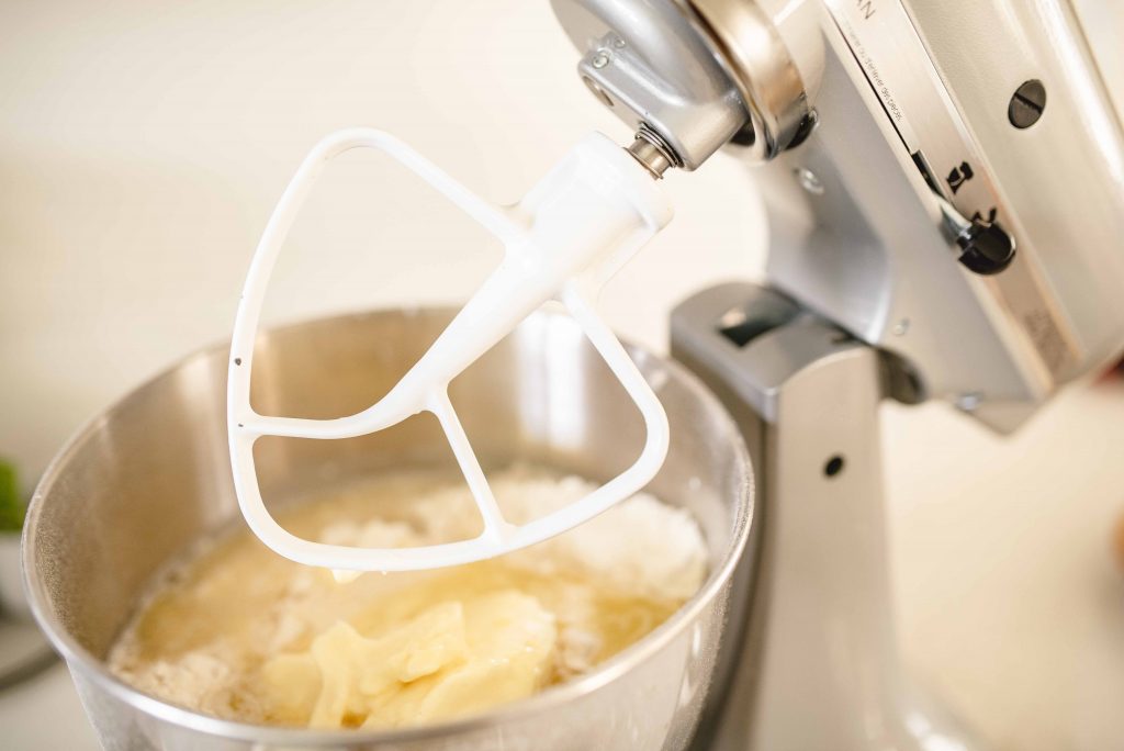 a kitchen aid mixer with a paddle attachment on a bowl with dough