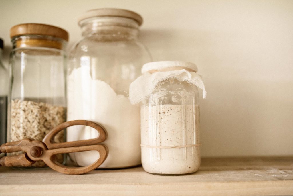 an open pantry with three glass jars and wooden scissors