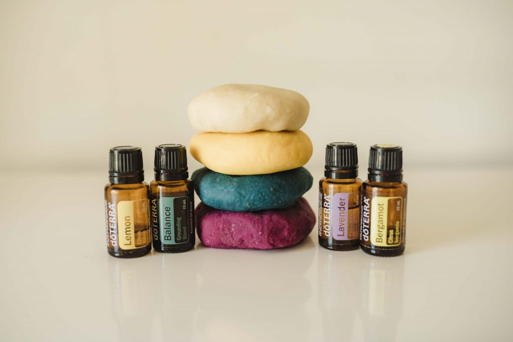 a colorful stack of playdough with lemon, balance, lavender, and bergamot essential oil bottles