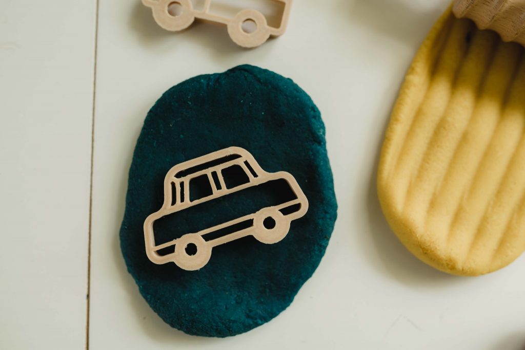 table with teal and yellow non-toxic playdough with an eco cutter car