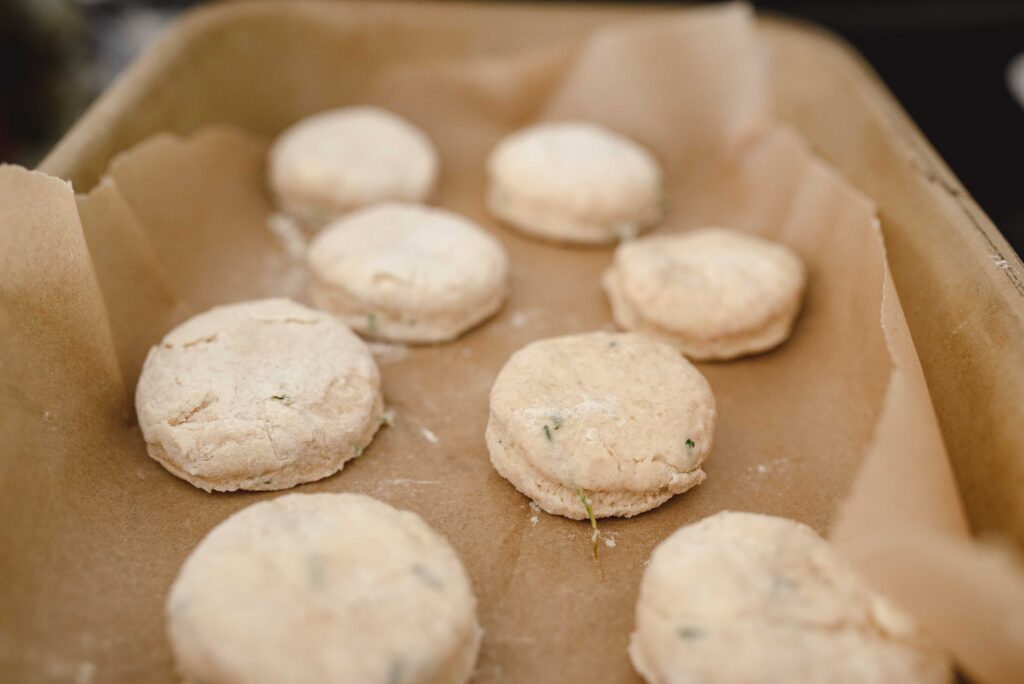 8 raw garlic chive sourdough biscuits sitting on parchment paper in a baking dish
