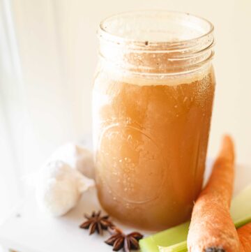a jar of instant pot bone broth in a mason jar with carrots, celery, garlic, and star anise