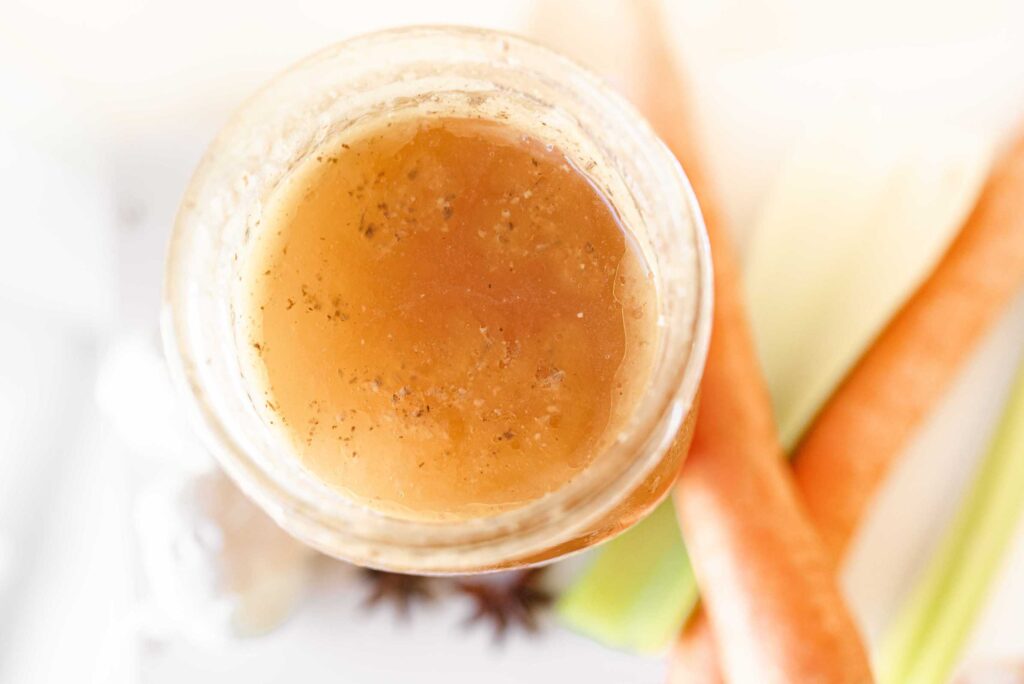 gelatin chicken bone broth in a clear mason jar with carrots and celery