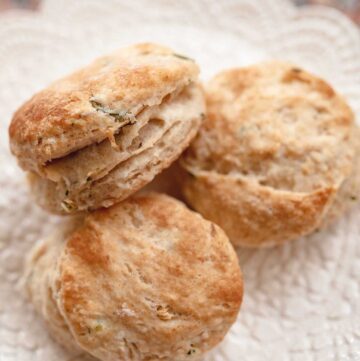 3 flaky garlic chive sourdough biscuits on a lace ceramic plate